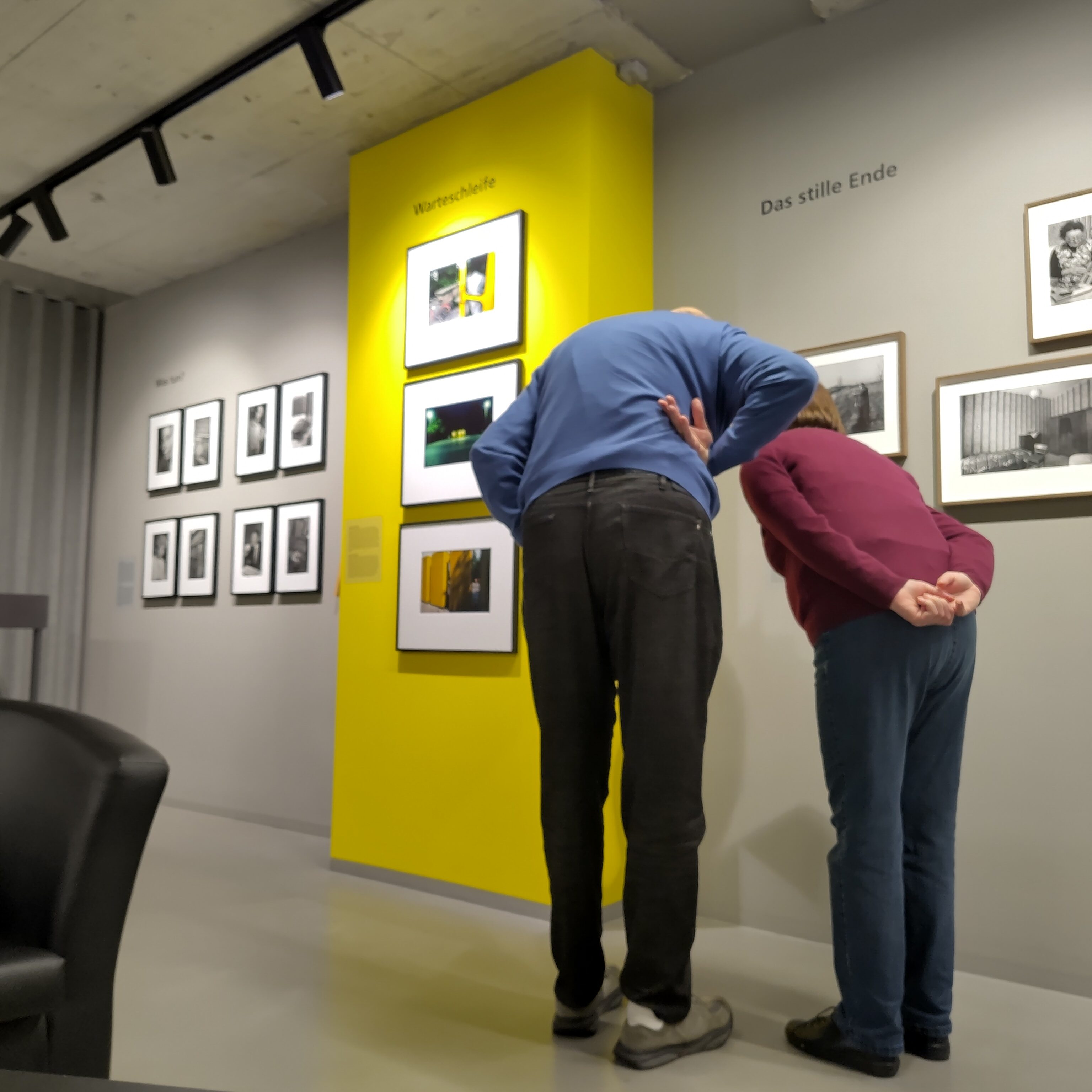 Zwei Menschen beugen sich vor ein Foto in einer Ausstellung, um es anzusehen.